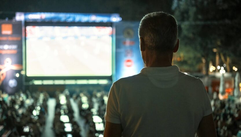 man-watching-football-public-place-night-online-sports-betting-singapore-change-life